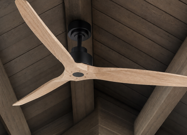 A three-blade ceiling fan with light natural wood blades and a matte black motor housing, shown installed on a dark wood-beamed ceiling.